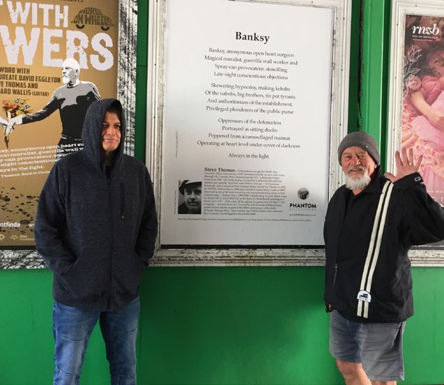 David Eggleton and Steve Thomas stand in front of part of a poetry campaign by Phantom.