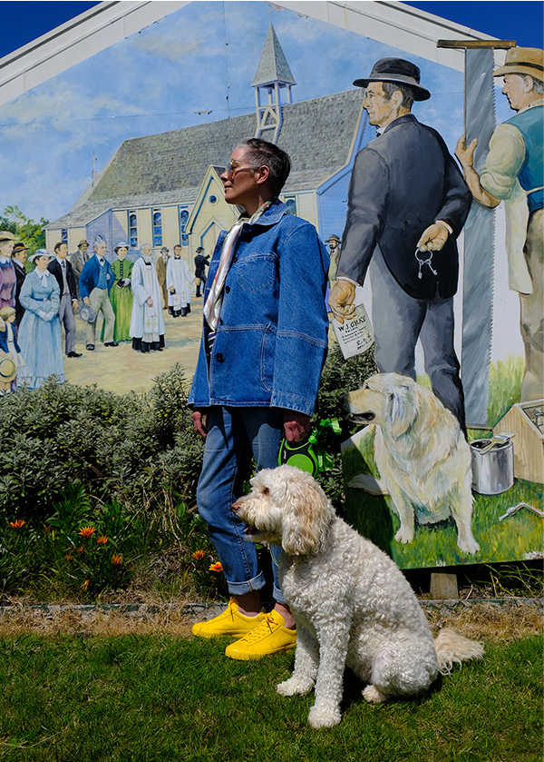 Karen Walker and her dog Laika in front of the image of her great-great grandfather.